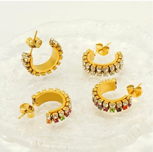 Détail macro de boucles d'oreilles C plaquées or 18K avec zircons blancs et colorés