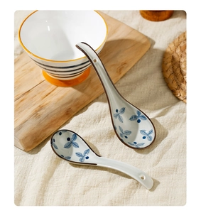 Detail of ceramic soup spoons with blue leaf patterns and brown rims on linen cloth
