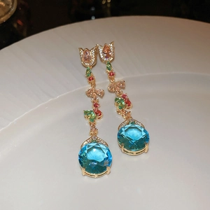 Detail view of tulip floral earrings with colorful zircons and large blue crystal drops