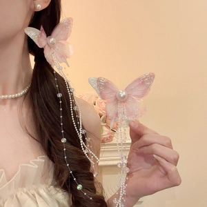 Close-up of butterfly hair clip with iridescent pink mesh wings and long pearl tassels