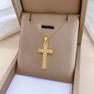 Detailed view of a gold cross pendant necklace with zircon stones in a jewelry gift box