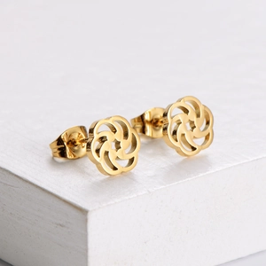 Elegant gold hollow floral stud earrings for women on a white geometric display stand