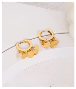 Detailed view of gold geometric hoop earrings with circular sequins on white stand