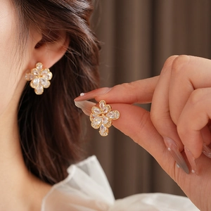 Detailed close-up of golden clover earrings with pear-cut cubic zirconia crystals