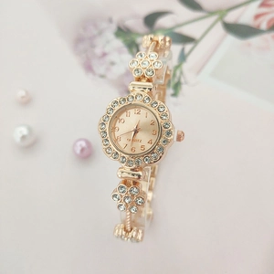 Close-up of gold flower watch dial with rhinestones and elegant quartz movement details