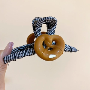 Détail d'une pince à cheveux en forme de cœur avec motif à carreaux et décor de bretzel