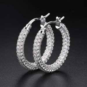 Luxe silver hoop earrings with full pave cubic zirconia on a matte black background