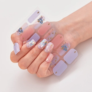 Close-up of holographic nail stickers with pink and purple glitter and gold foil accents