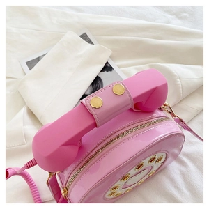 Detail of pink faux leather telephone handbag with receiver handle and dial texture