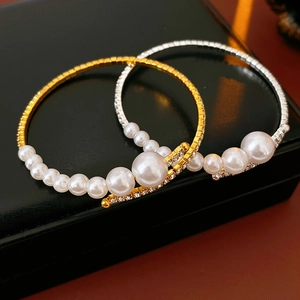 Close-up of gold and silver bangle set with sparkling rhinestones and white imitation pearls