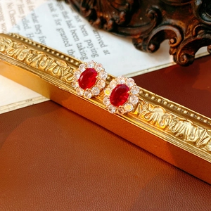 Makroaufnahme ovaler roter Zirkon-Ohrringe mit Goldfassung auf Vintage-Hintergrund
