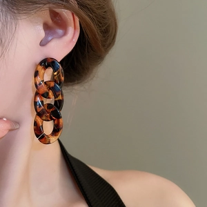 Close-up of tortoise shell resin chain earrings on model with Maillard aesthetic
