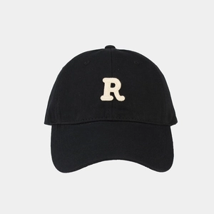 Dettaglio del ricamo beige 3D della lettera R su un cappellino da baseball nero in cotone