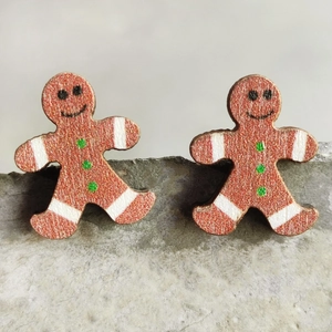 Macro shot of gingerbread man wooden stud earrings featuring white lines and green buttons