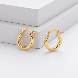 Detailed shot of polished S925 sterling silver gold-plated hoop earrings on a white block