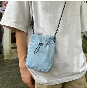 Detail of light blue waterproof nylon mini crossbody bag with drawstring and woven strap
