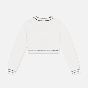 Detail view of the back of a white knit cardigan with black contrast trim and fine texture