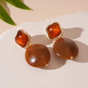 Detail of amber resin drop earrings with tortoiseshell texture and gold-plated frames