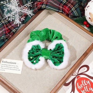 Green velvet Christmas bow scrunchie with white faux fur trim and sequins on festive tray