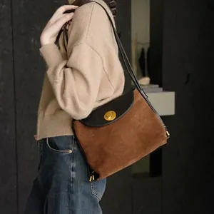 Detail of vintage leather crossbody bag with brown suede and gold twist-lock closure
