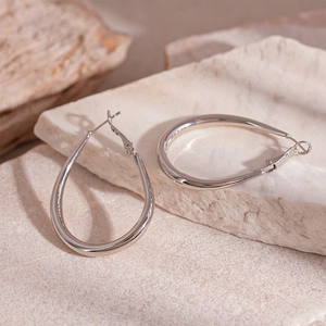 Polished silver pear-shaped drop earrings displayed on natural stone texture