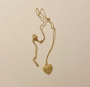 Detail of S925 hallmark on a gold heart necklace with engraved Yes Maybe No text