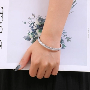 Detail view of a silver twisted rope cuff bracelet worn by a model against a clean card