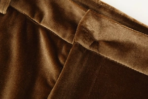 Macro shot of dark brown velvet fabric texture and waist tailoring on flared trousers