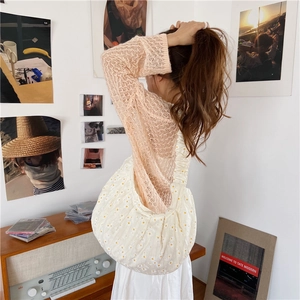 Detail of cream canvas shoulder bag with daisy print in a warm lifestyle aesthetic
