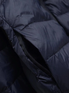 Detail of navy blue quilted puffer jacket with smooth invisible zipper pocket closure