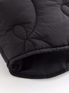 Close-up of black quilted jacket detailing waves stitching and smooth fabric texture