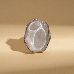Detailed view of silver irregular oval ring with molten texture on beige leather