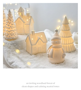 Macro view of matte white ceramic Christmas house with warm LED glowing through windows