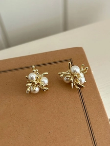 Macro shot of 18k gold plated pearl earrings with irregular floral branch design