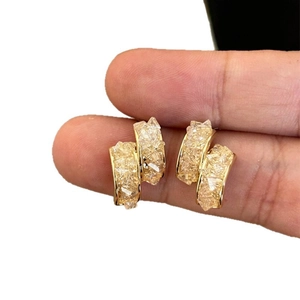 Boucles d'oreilles plaquées or 14k avec pierres en verre texturées montrées sur doigts.