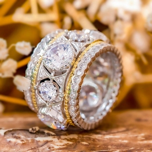 Macro view of luxurious two-tone wide band ring with three large white zircons in vintage style