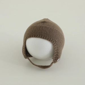 Dettaglio cappello a maglia per neonati con paraorecchie, laccetti e bottone chiaro