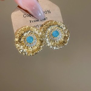 Macro detail of vintage gold floral earrings with turquoise center and zircon accents