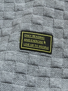 Detail of grey knitted fabric with 3D grid texture and yellow embroidered text patch