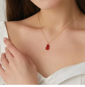 Macro shot of natural red agate gourd pendant necklace worn on a gold collar chain