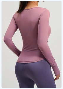 Dettaglio del top da yoga rosa a maniche lunghe con vita arricciata e leggings viola