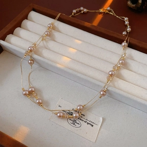 Close-up of double-layer gold chain with pink faux pearls and crystal beads in a box