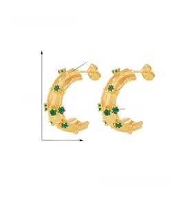 Detail view of 18k gold plated C-shape hoop earrings with green glass stones and copper base