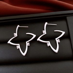 Macro shot of silver starburst hollow earrings displayed on a premium black jewelry stand