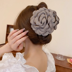 Detail view of a large grey fabric camellia flower hair claw clip on a woman's hair