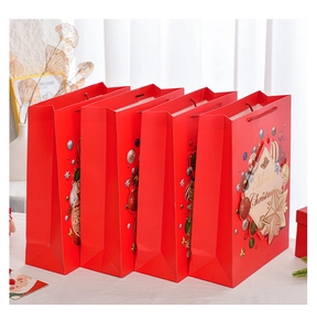 Detail of four red Christmas gift bags with Merry Christmas text and festive star pattern