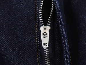 Gros plan sur le zip en métal argenté et le tissu en denim bleu foncé robuste