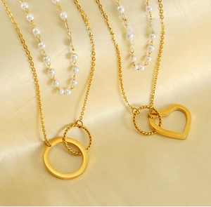 Vue macro de colliers double rang dorés avec pendentifs cœur et perles blanches sur soie