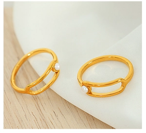 Detailed close-up of two gold titanium rings with small pearls on a clean fabric background