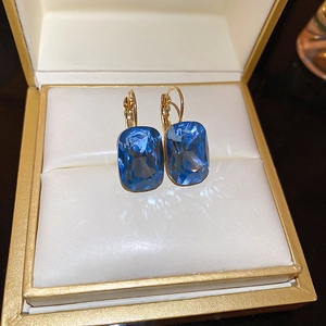Macro shot of cushion-cut blue gemstone lever-back earrings on a white jewelry tray